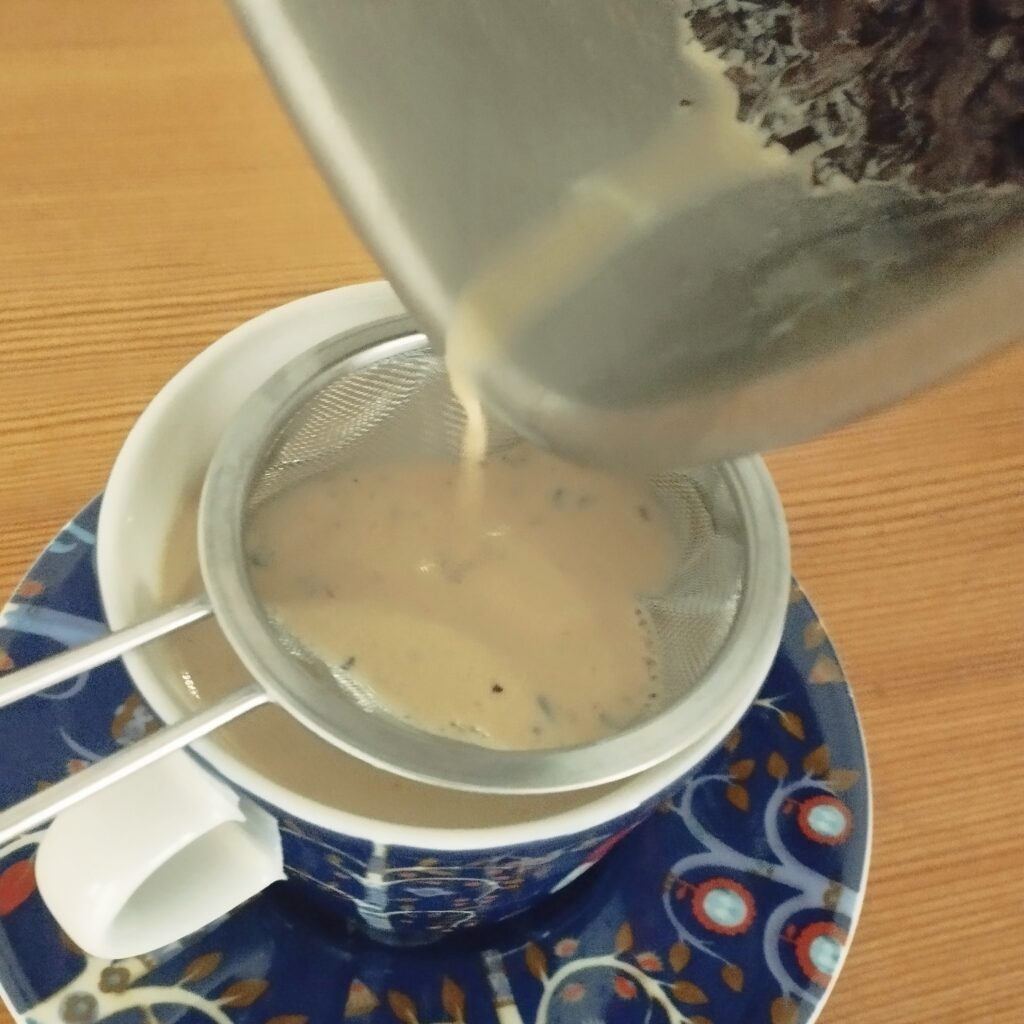 イッタラのカップ＆ソーサーにミルクパンからチャイを注いでいるところの写真です